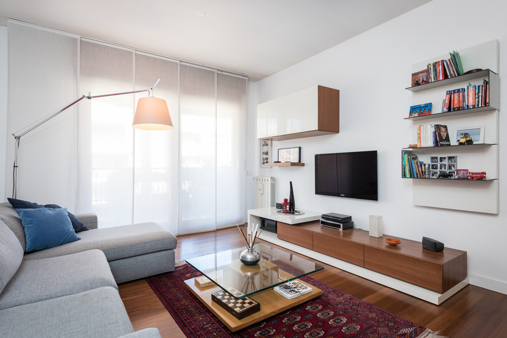 Immagine di un soggiorno minimalista con pareti bianche, pavimento in legno massello medio, nessun camino e TV a parete