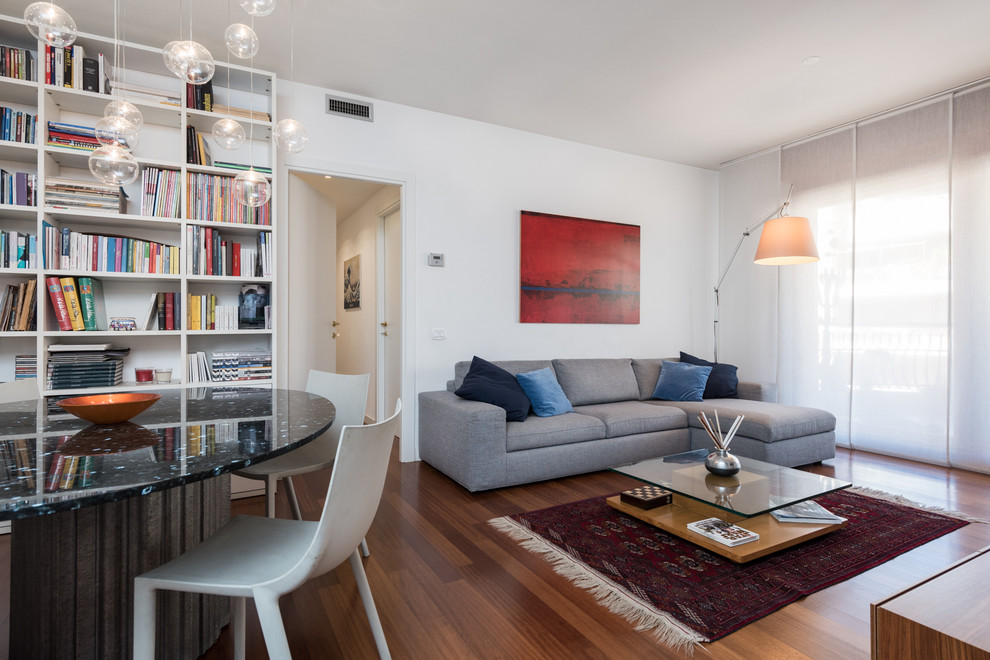 Immagine di un ampio soggiorno moderno aperto con pareti bianche, pavimento in legno massello medio, nessun camino, libreria e nessuna TV