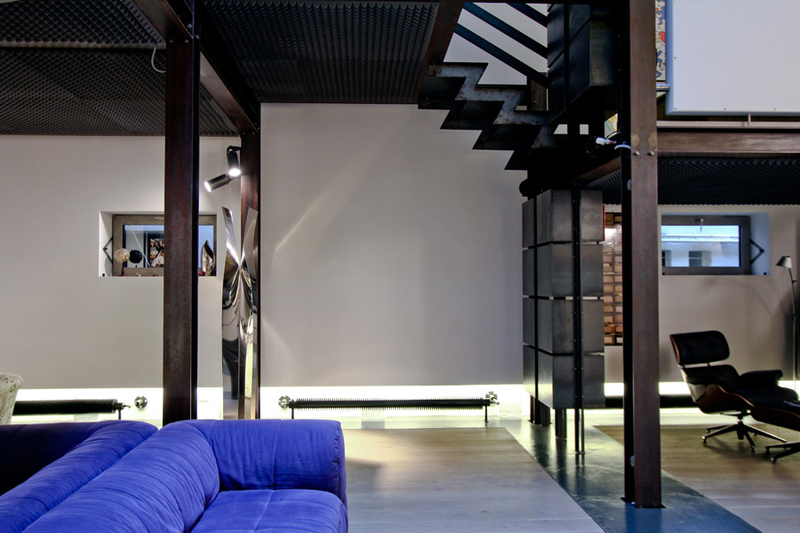 Diseño de sala de estar con rincón musical tipo loft industrial grande con paredes blancas, suelo de madera clara y televisor retractable