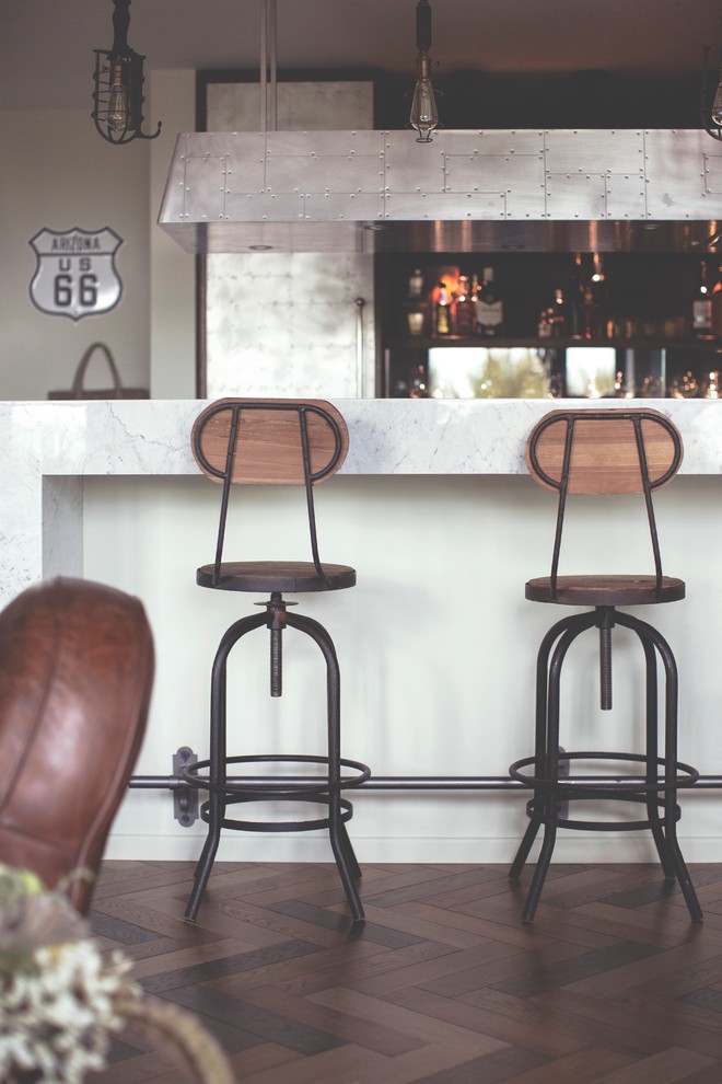 Imagen de salón con barra de bar abierto industrial de tamaño medio con paredes grises, suelo de madera en tonos medios y suelo marrón