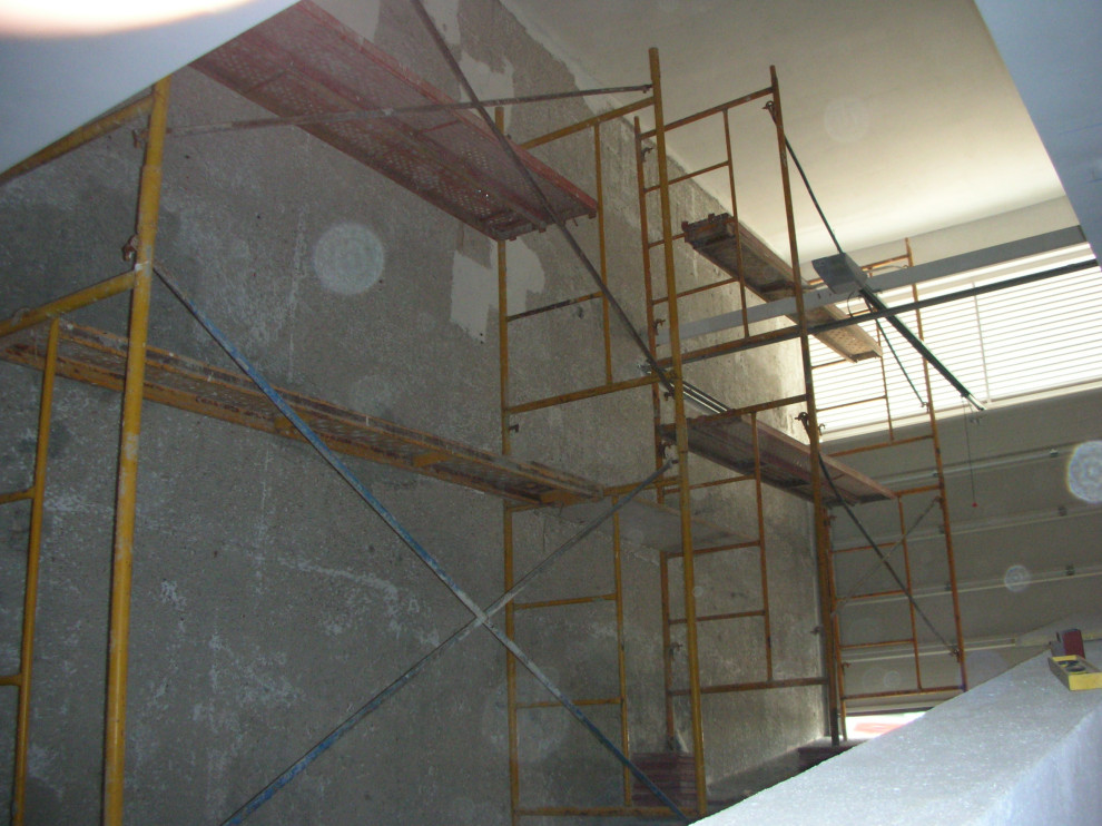 Aménagement d'un très grand sous-sol contemporain semi-enterré avec un mur blanc, sol en béton ciré et un sol rouge.