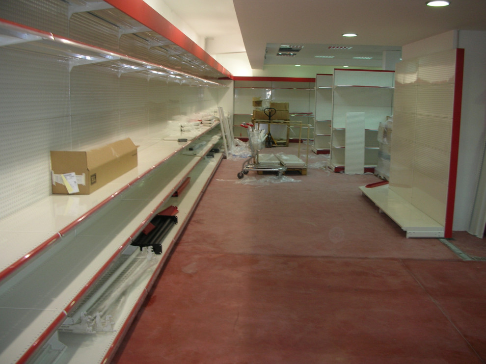 Idee per un'ampia taverna design seminterrata con pareti bianche, pavimento in cemento e pavimento rosso