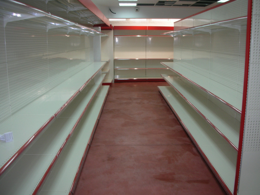 Bild på en mycket stor funkis källare utan ingång, med vita väggar, betonggolv och rött golv