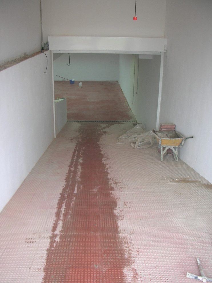 Idée de décoration pour un très grand sous-sol design semi-enterré avec un mur blanc, sol en béton ciré et un sol rouge.