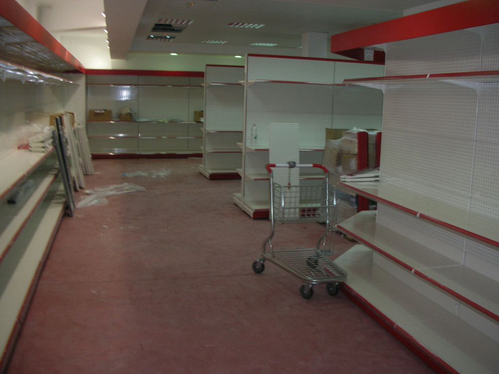 Bild på en mycket stor funkis källare utan ingång, med vita väggar, betonggolv och rött golv