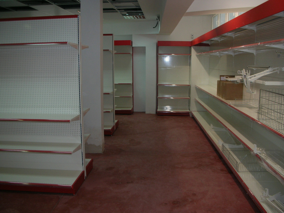 Exempel på en mycket stor modern källare utan ingång, med vita väggar, betonggolv och rött golv