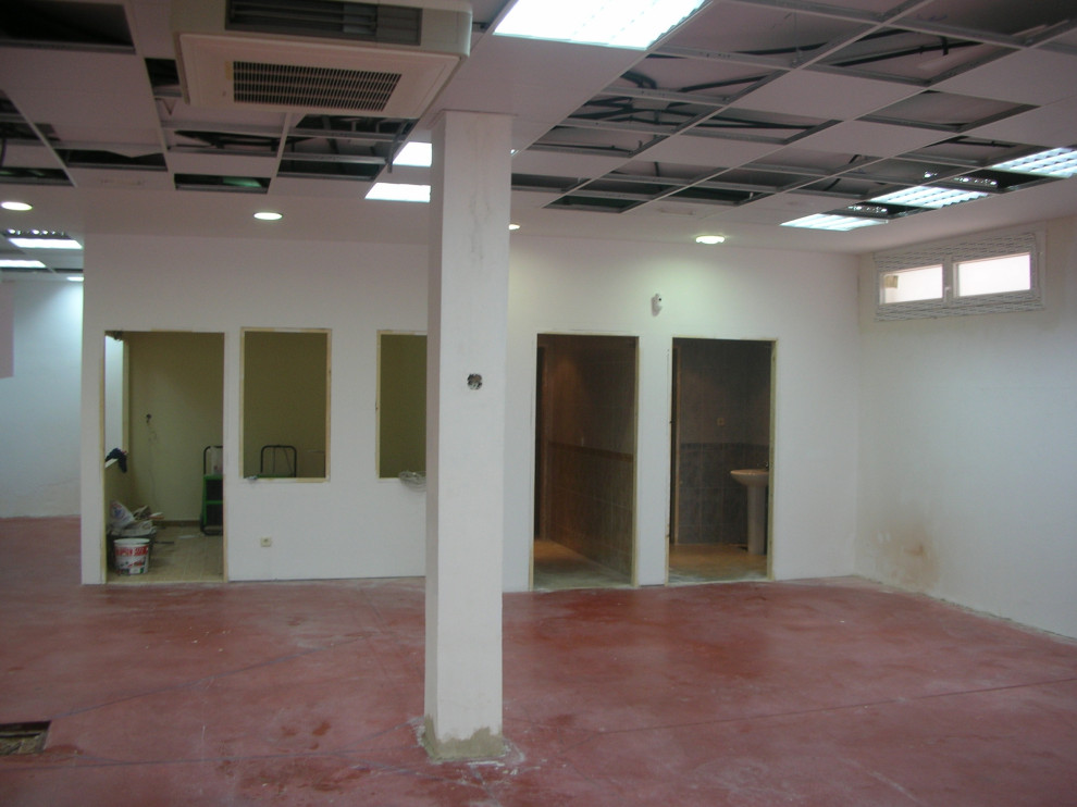 На фото: огромный подвал в современном стиле с наружными окнами, белыми стенами, бетонным полом и красным полом