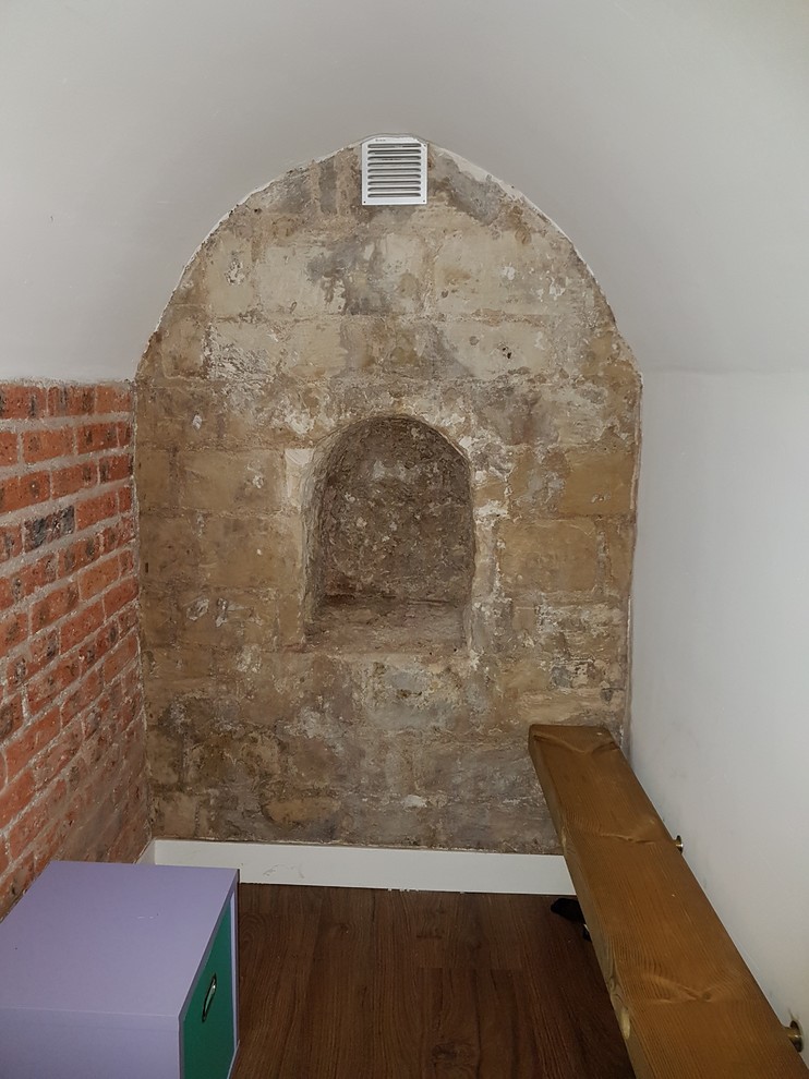 Cette image montre un petit sous-sol design enterré avec un mur blanc, un sol en linoléum et un sol marron.