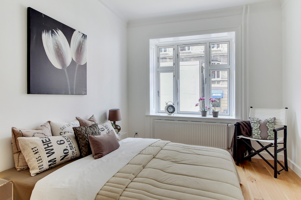Photo of a small scandi bedroom in Copenhagen with white walls, light hardwood flooring, no fireplace and beige floors.
