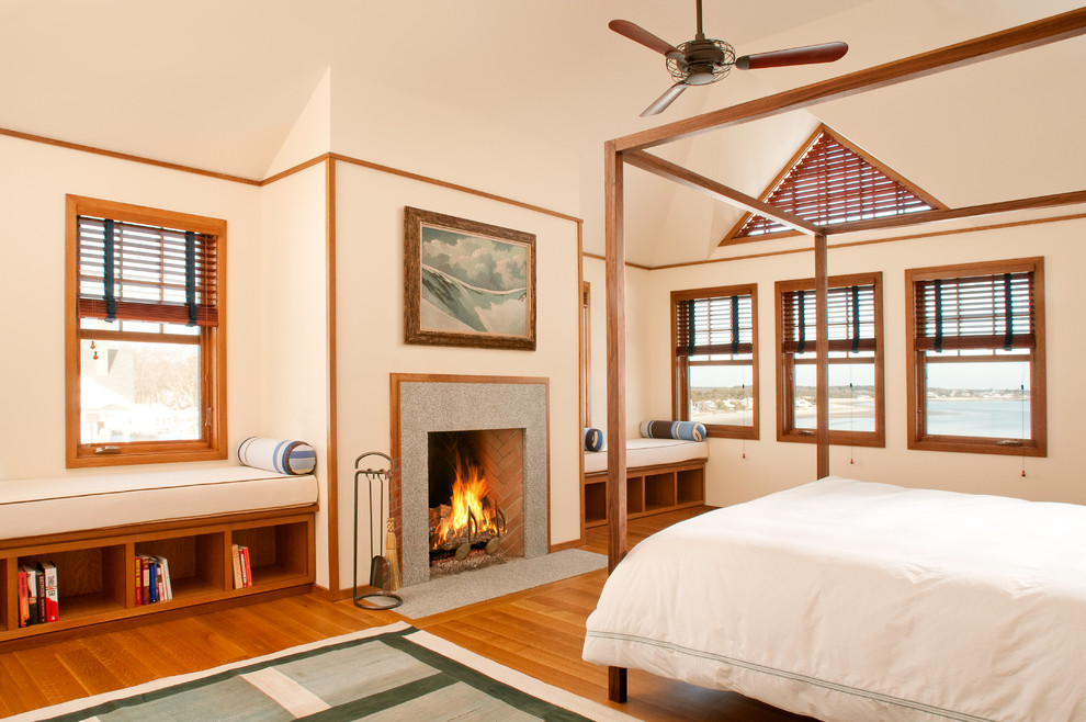 Imagen de dormitorio de estilo americano con paredes blancas, suelo de madera en tonos medios, chimenea de doble cara, marco de chimenea de baldosas y/o azulejos y suelo marrón