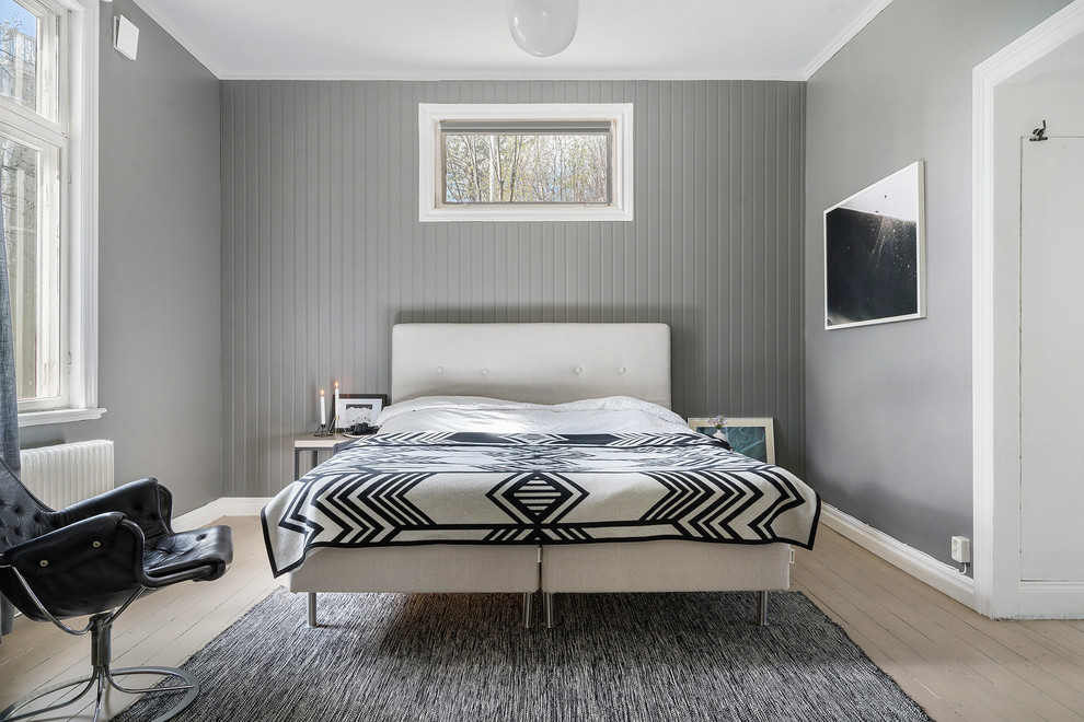 This is an example of a scandi grey and white bedroom in Copenhagen with grey walls, beige floors and painted wood flooring.
