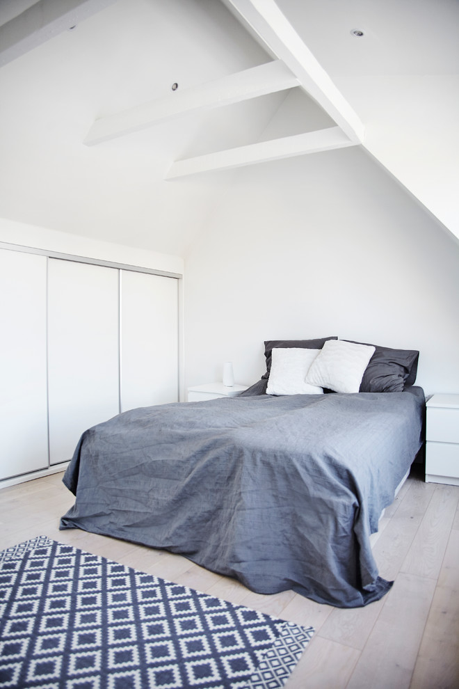 Großes Nordisches Hauptschlafzimmer ohne Kamin mit weißer Wandfarbe und hellem Holzboden in Sonstige
