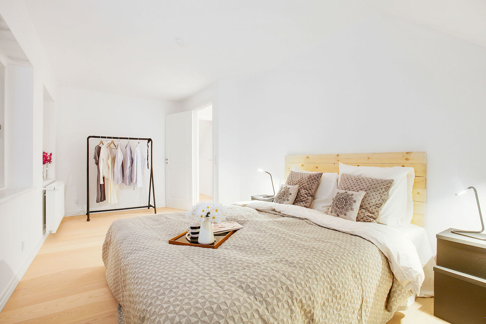 На фото: большая хозяйская спальня в скандинавском стиле с белыми стенами и светлым паркетным полом без камина
