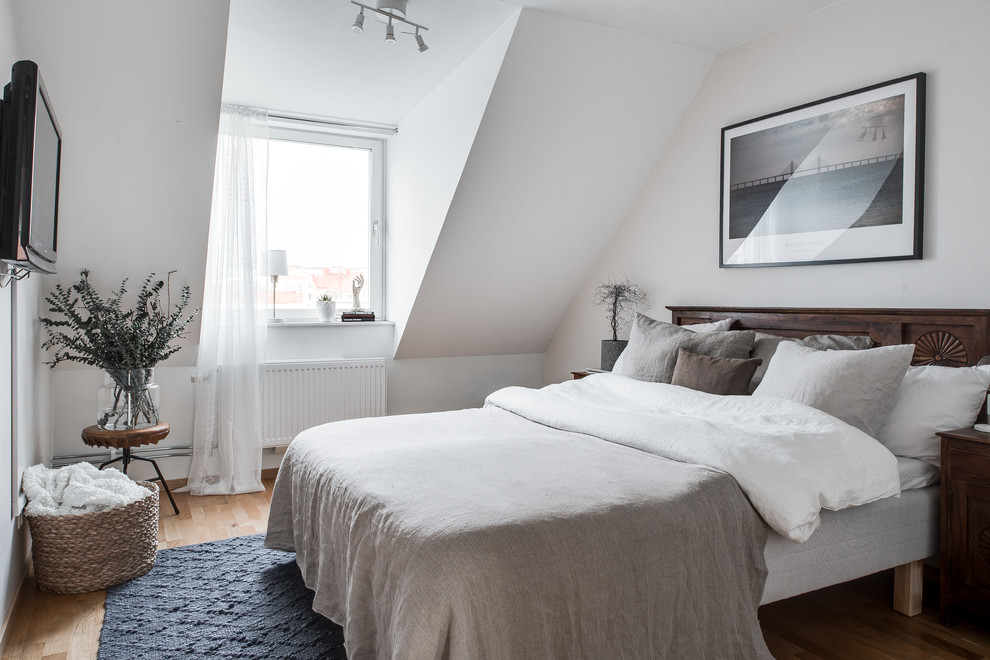 На фото: хозяйская спальня среднего размера в скандинавском стиле с белыми стенами, светлым паркетным полом и телевизором без камина