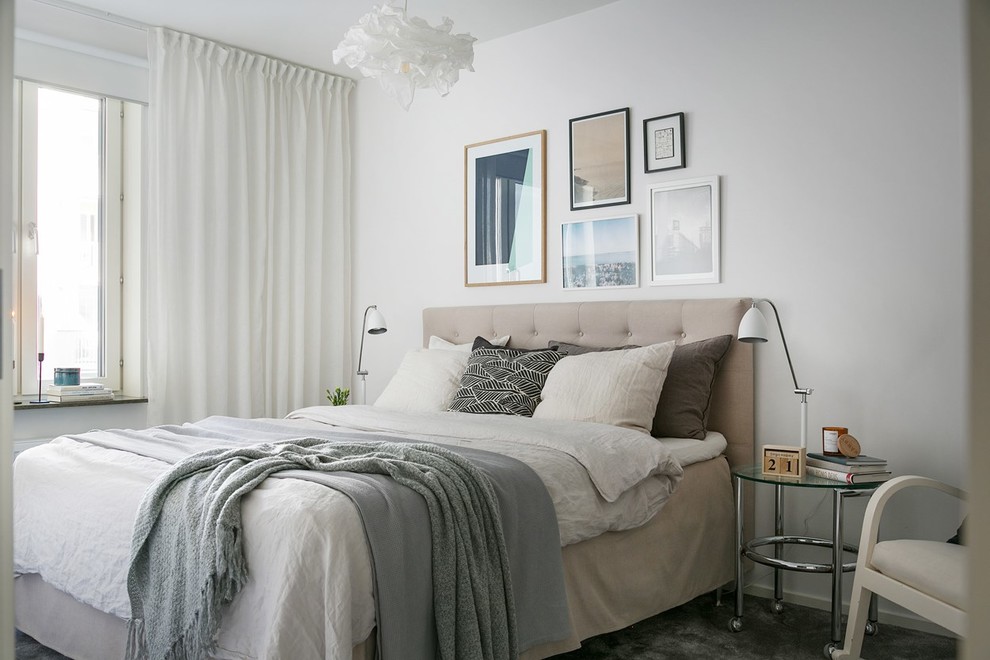 Foto på ett minimalistiskt sovrum, med vita väggar, heltäckningsmatta och grått golv