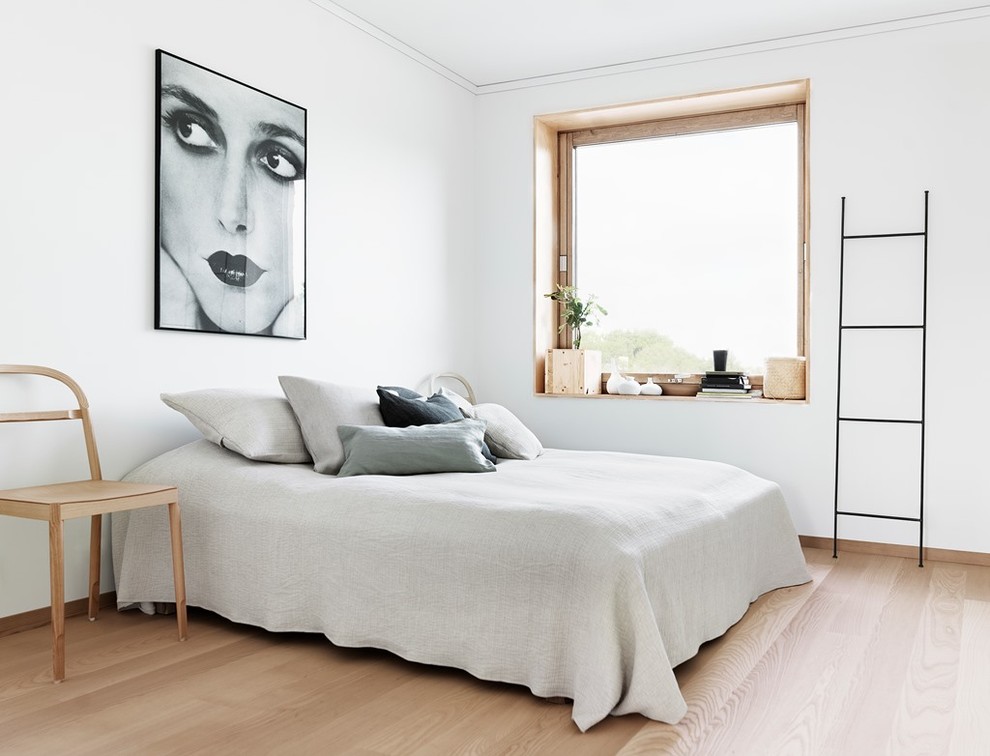 Photo of a medium sized scandinavian master bedroom in Stockholm with white walls, light hardwood flooring and no fireplace.