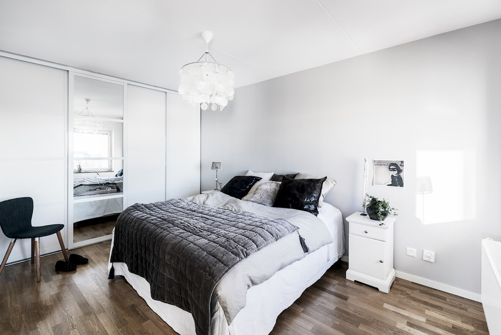 Foto på ett minimalistiskt huvudsovrum, med vita väggar, mellanmörkt trägolv och brunt golv