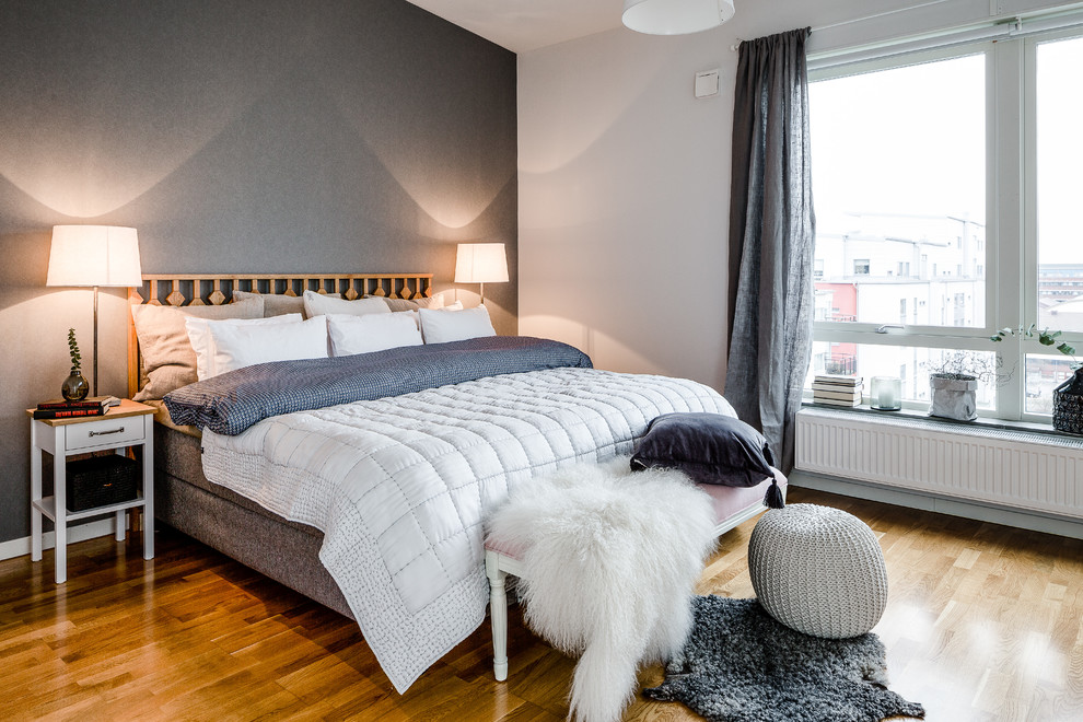 На фото: большая хозяйская спальня в скандинавском стиле с серыми стенами, светлым паркетным полом и акцентной стеной