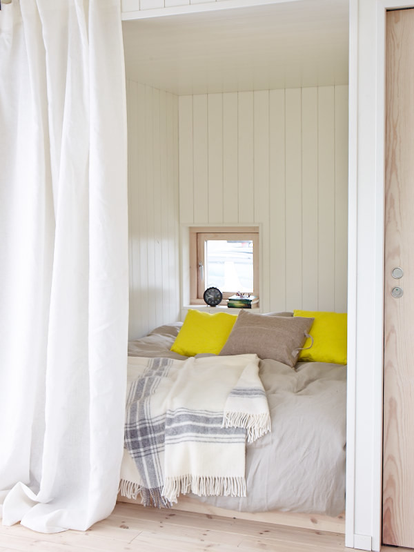 Inredning av ett minimalistiskt litet gästrum, med vita väggar och ljust trägolv