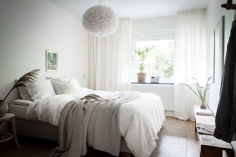 Inspiration för ett nordiskt sovrum, med vita väggar, ljust trägolv och beiget golv
