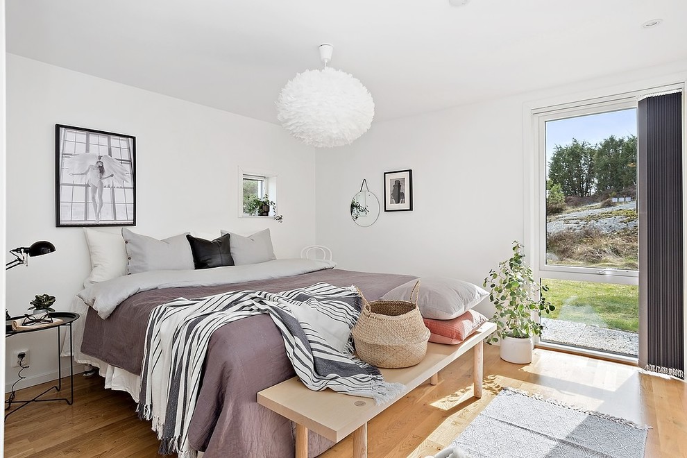 Foto på ett skandinaviskt sovrum, med vita väggar och ljust trägolv