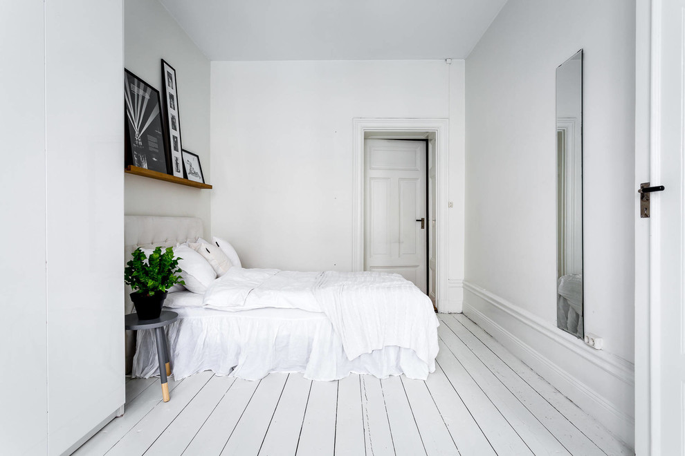 Immagine di una camera matrimoniale nordica di medie dimensioni con pareti bianche e pavimento in legno verniciato