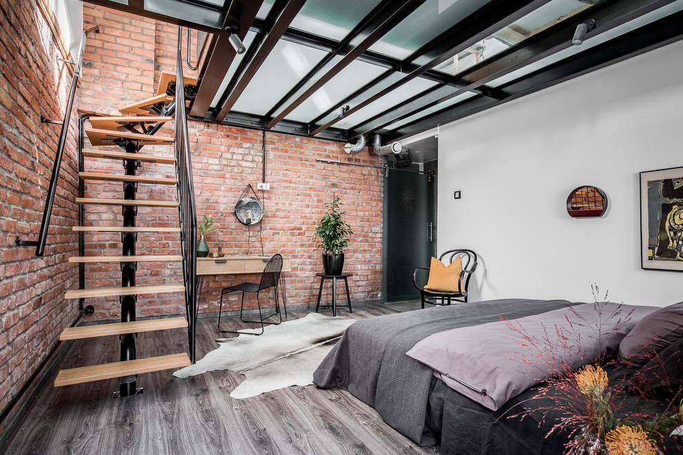 Ejemplo de dormitorio principal industrial de tamaño medio con parades naranjas, suelo de madera en tonos medios y suelo gris