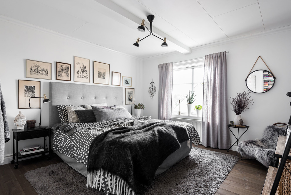 Großes Nordisches Hauptschlafzimmer ohne Kamin mit weißer Wandfarbe und dunklem Holzboden in Göteborg