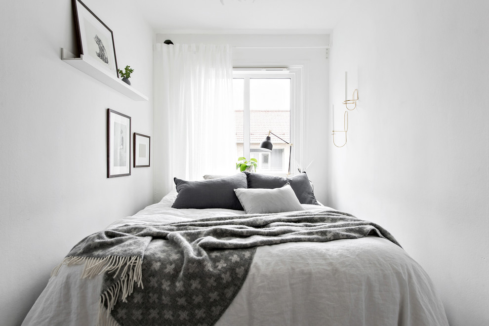 На фото: маленькая хозяйская, серо-белая спальня в скандинавском стиле с белыми стенами для на участке и в саду