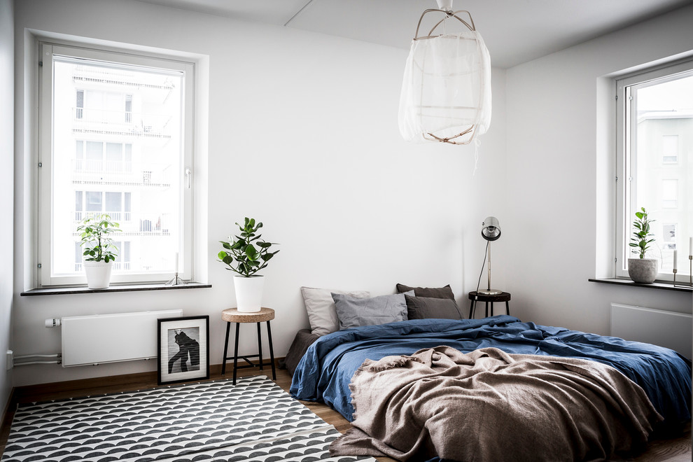 ストックホルムにある中くらいな北欧スタイルのおしゃれな主寝室 (白い壁、無垢フローリング)