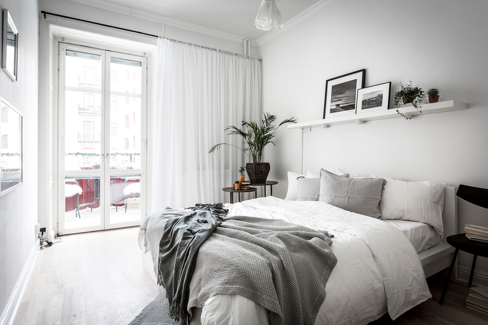 Immagine di una camera matrimoniale scandinava di medie dimensioni con pareti bianche e parquet chiaro