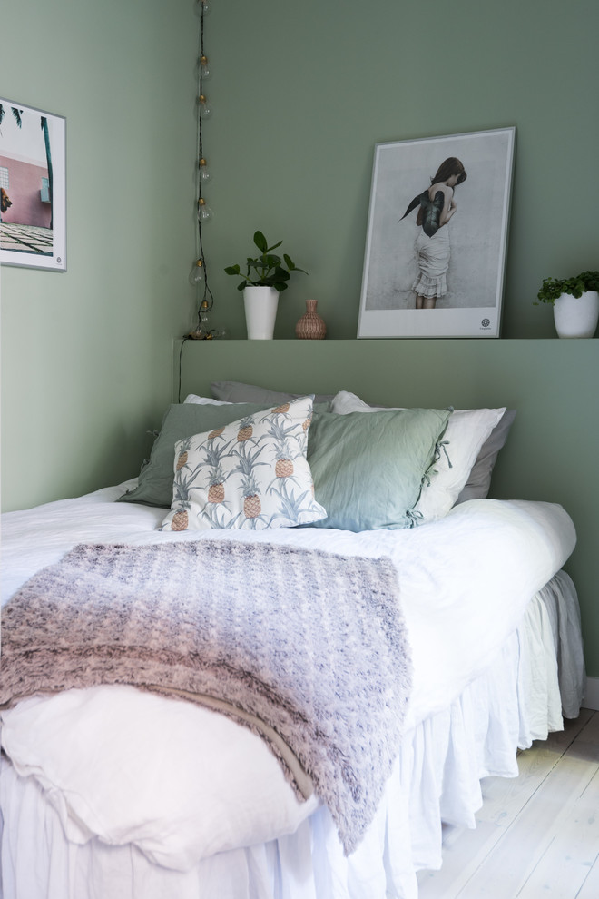 Cette image montre une petite chambre d'amis nordique avec un mur vert, parquet clair et un sol blanc.