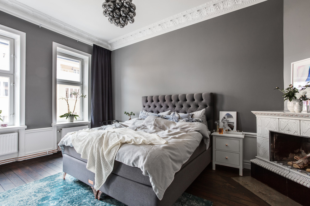 Пример оригинального дизайна: хозяйская спальня в скандинавском стиле с серыми стенами, темным паркетным полом, угловым камином, фасадом камина из плитки и коричневым полом