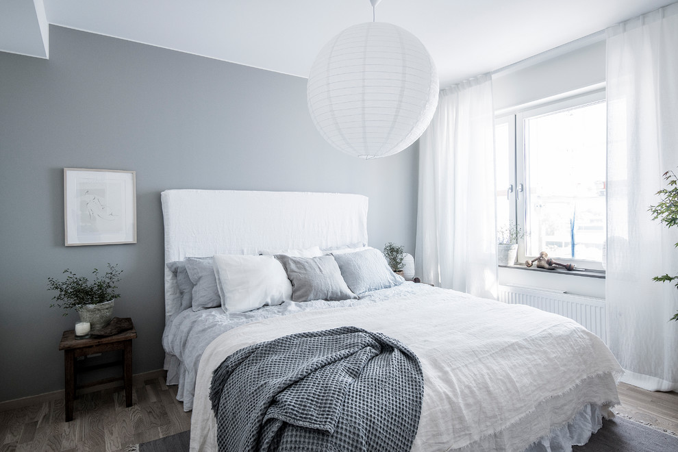 Diseño de dormitorio escandinavo de tamaño medio con paredes grises, suelo de madera en tonos medios y suelo gris