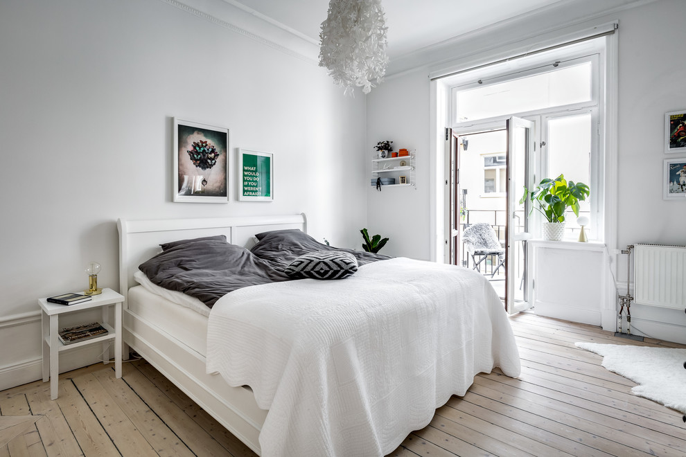 Medium sized scandi master bedroom in Stockholm with white walls and light hardwood flooring.