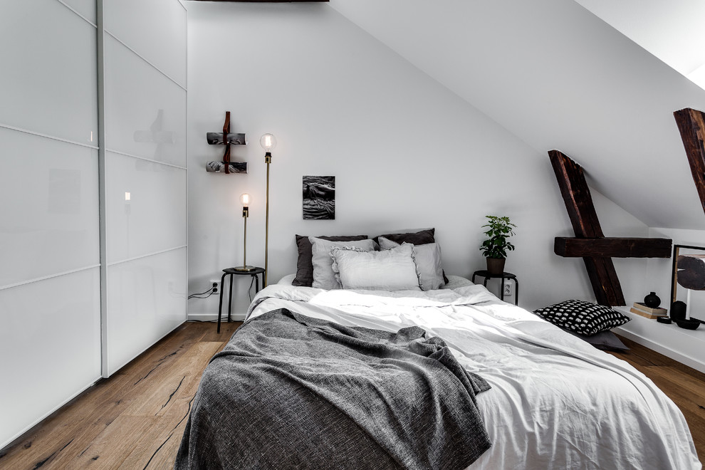 This is an example of a medium sized scandinavian bedroom in Stockholm with white walls and medium hardwood flooring.