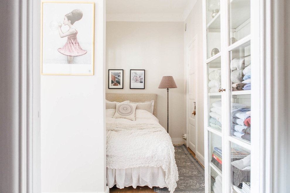 Medium sized vintage master bedroom in Stockholm with white walls, medium hardwood flooring and no fireplace.