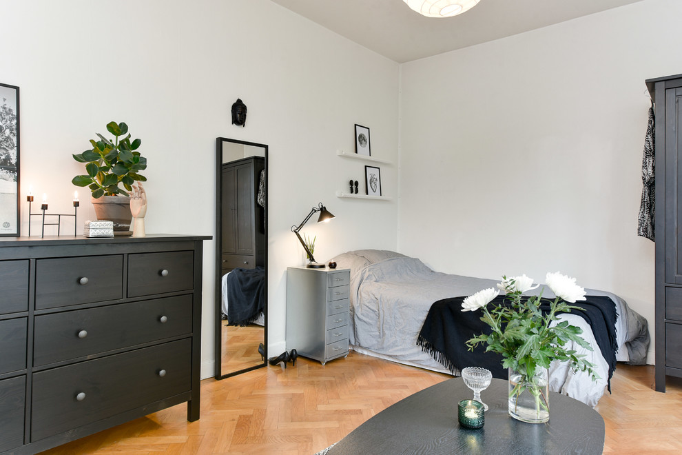 Mittelgroßes Nordisches Hauptschlafzimmer ohne Kamin mit weißer Wandfarbe und braunem Holzboden in Stockholm