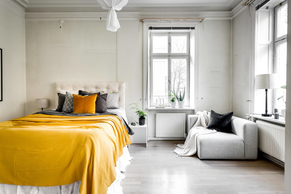 This is an example of a medium sized scandinavian master bedroom in Stockholm with white walls and light hardwood flooring.