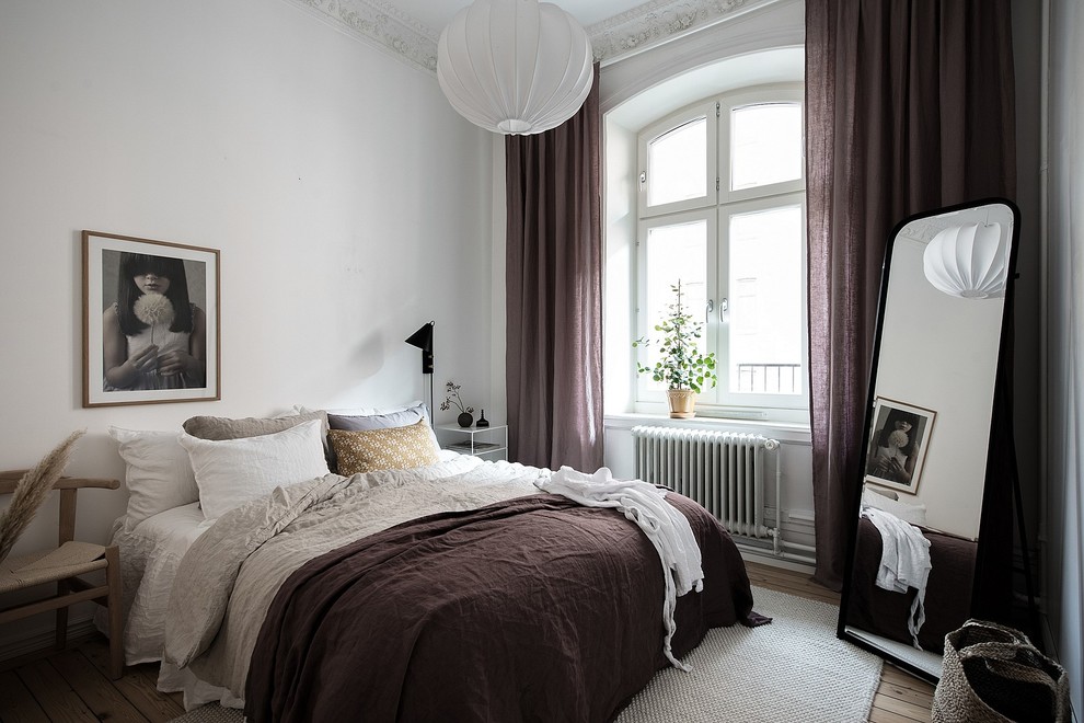 Bild på ett minimalistiskt sovrum, med vita väggar, ljust trägolv och beiget golv