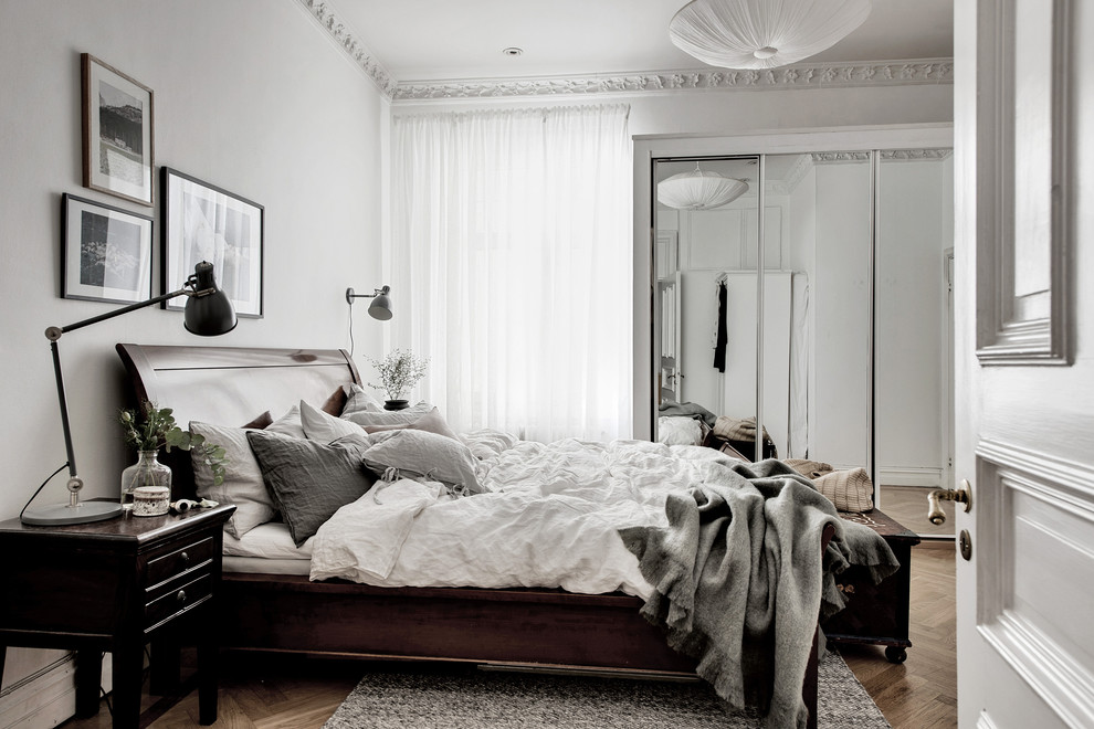 Diseño de dormitorio principal escandinavo grande con paredes blancas, suelo de madera en tonos medios y suelo marrón