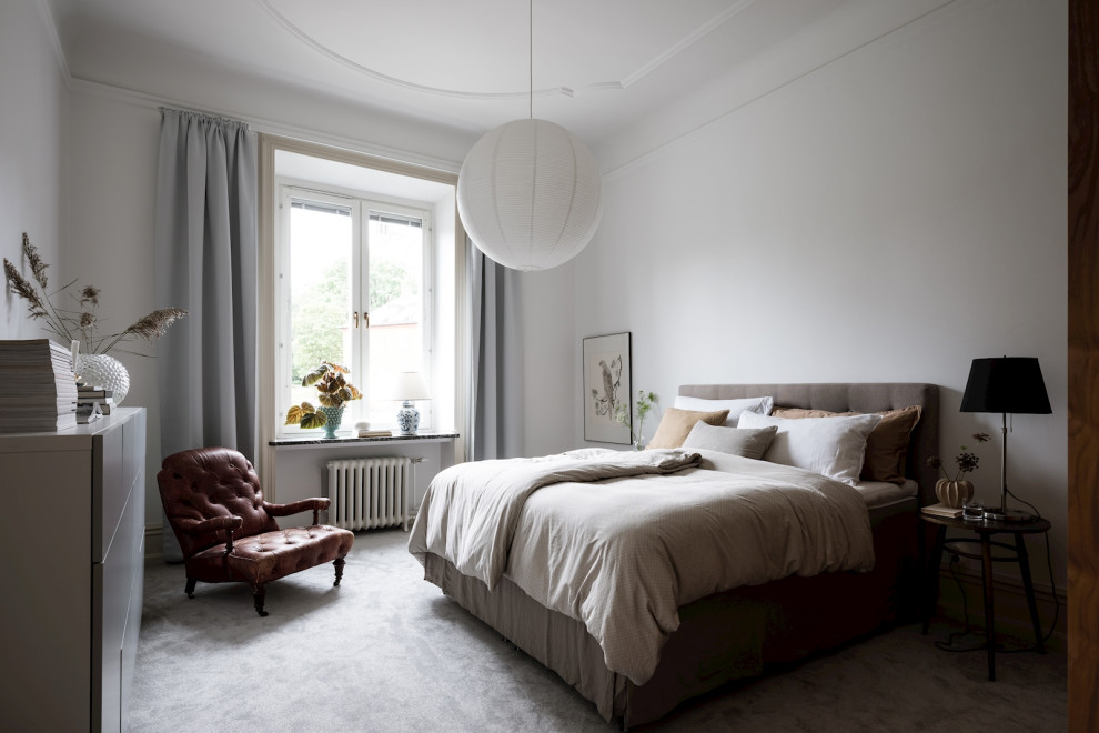 Foto på ett minimalistiskt sovrum, med vita väggar, heltäckningsmatta och grått golv