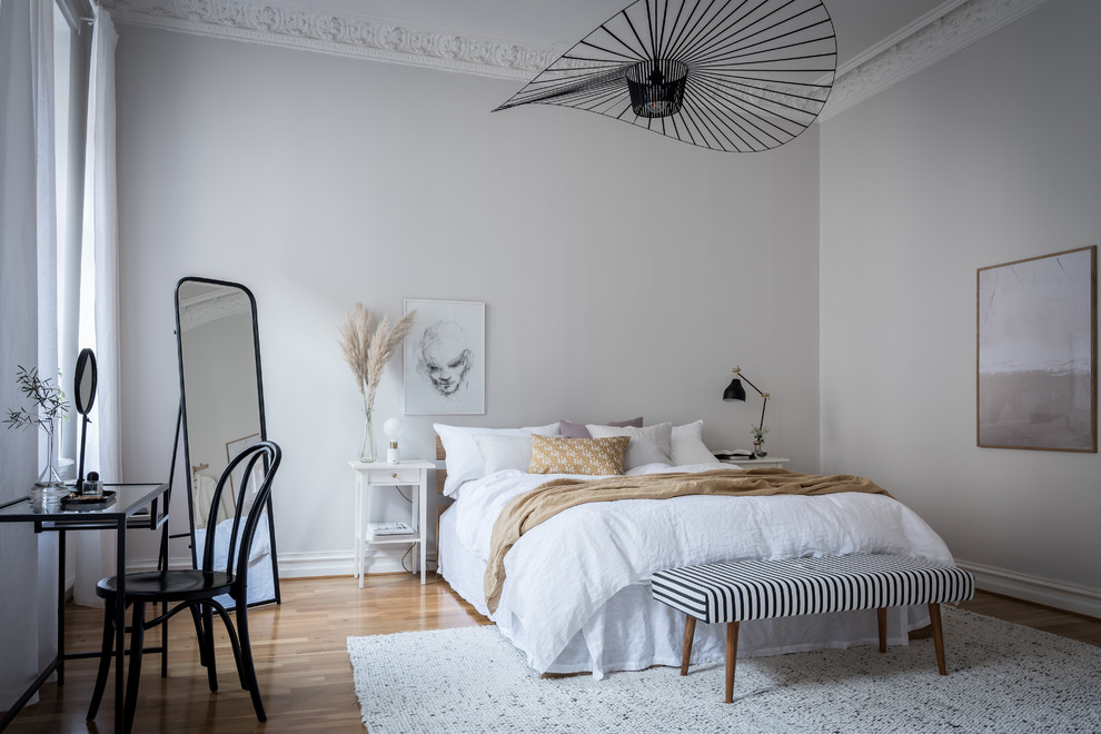 Diseño de dormitorio nórdico con paredes grises, suelo de madera en tonos medios y suelo marrón