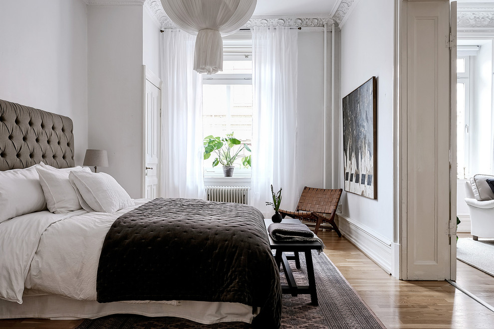 Inspiration for a medium sized scandi master bedroom in Gothenburg with white walls, medium hardwood flooring, no fireplace and brown floors.