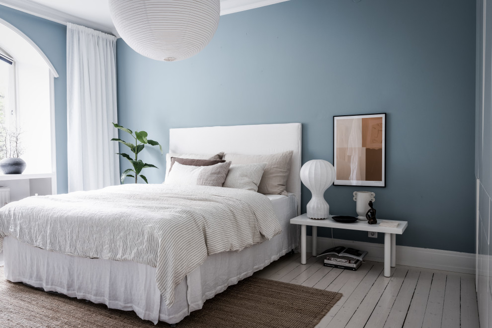 Photo of a scandi bedroom in Gothenburg with blue walls, painted wood flooring and white floors.