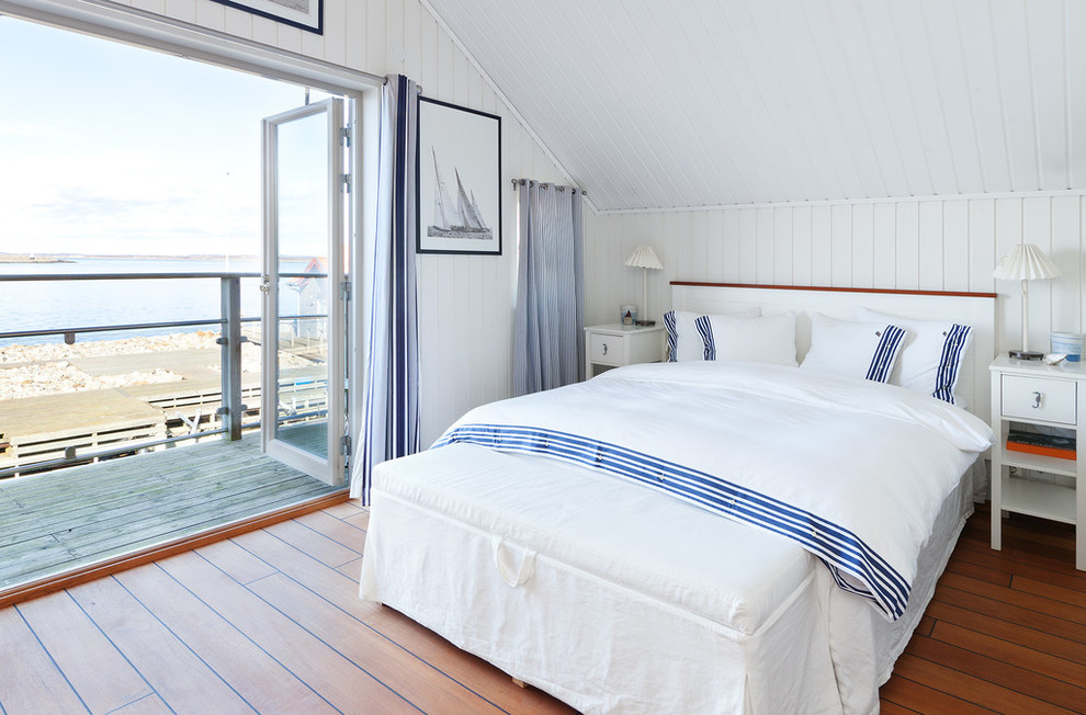 Modelo de dormitorio principal marinero de tamaño medio sin chimenea con paredes blancas y suelo de madera en tonos medios