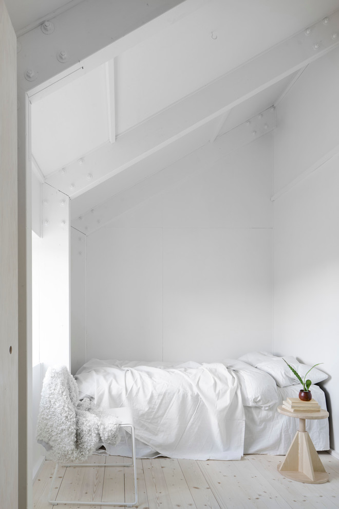 マルメにある小さな北欧スタイルのおしゃれな客用寝室 (白い壁、淡色無垢フローリング、暖炉なし、勾配天井) のインテリア