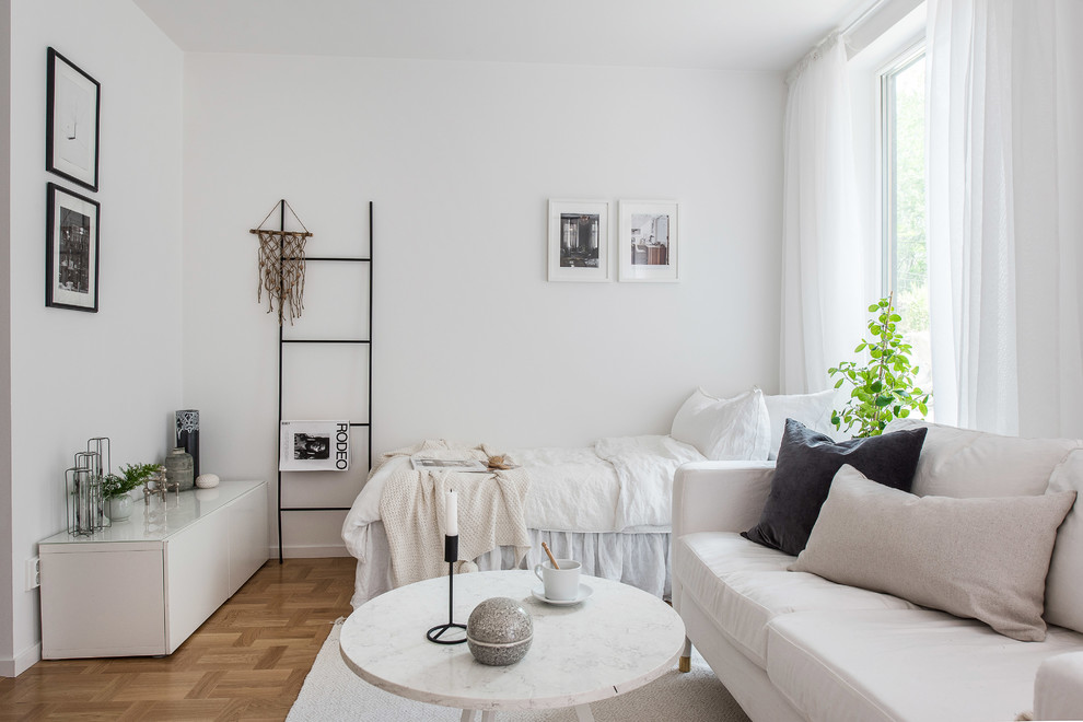 This is an example of a small scandi bedroom in Stockholm with white walls and medium hardwood flooring.