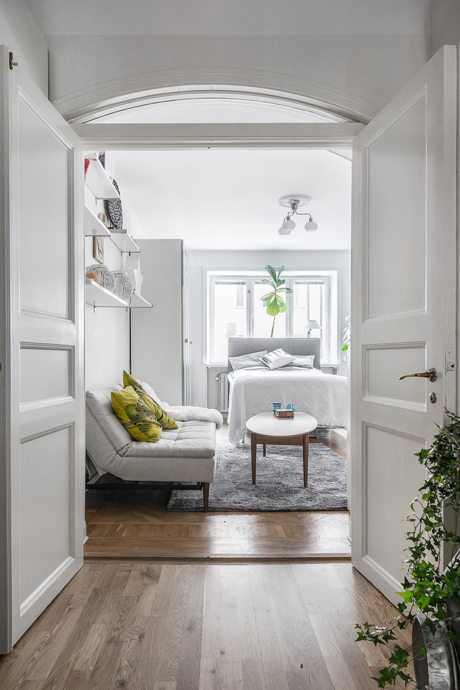 Bild på ett mellanstort minimalistiskt sovrum, med vita väggar, mellanmörkt trägolv och brunt golv
