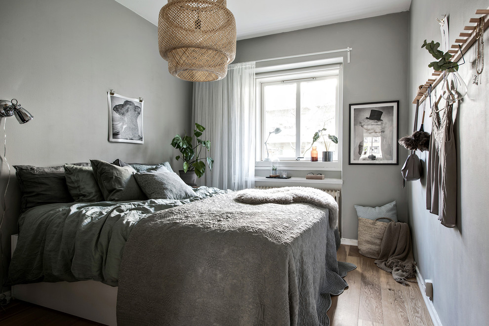 Small scandinavian bedroom in Gothenburg with grey walls, medium hardwood flooring, no fireplace and brown floors.